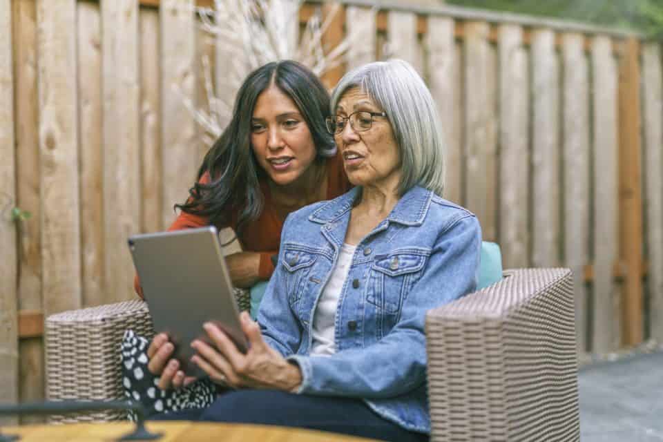 Senior woman learning to use tablet computer with the help of her adult daughter