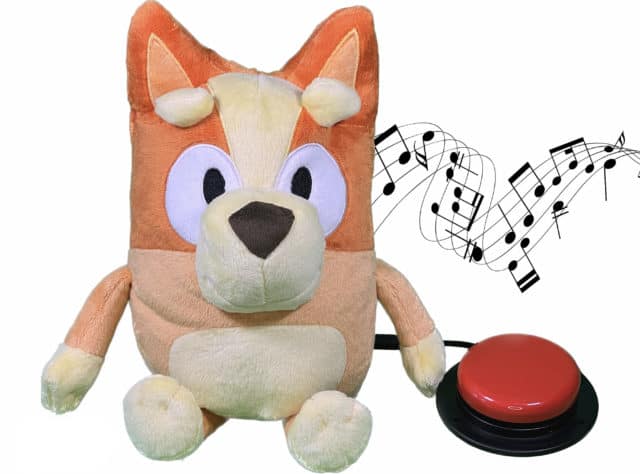 Toy dog with red switch attached. There is a music icon beside him, indicating that music is playing.