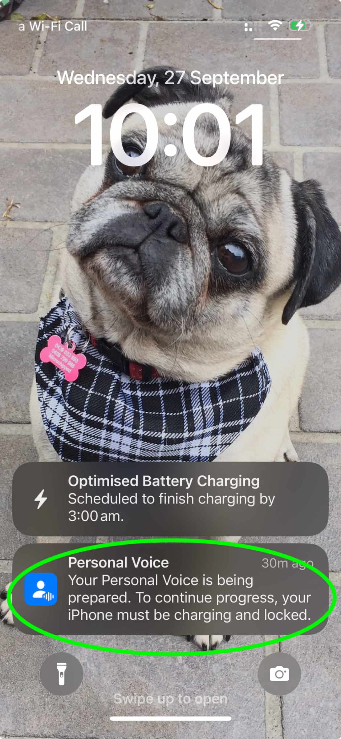 A screenshot of an iPhone on lock screen with a notification stating that "Your Personal Voice is being prepared. To continue progress, your iPhone must be charging and locked."
